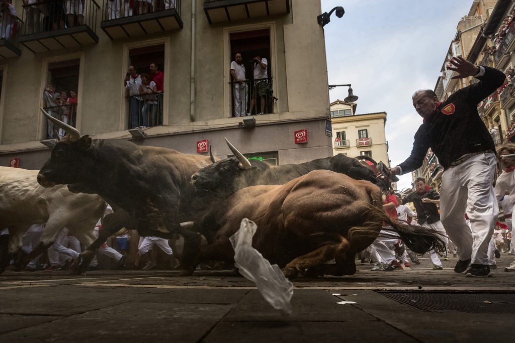 Revelers run chased by 'El Tajo y La Reina' ranch fighting bulls as they turn Estafeta corner during a running of the bulls of the San Fermin festival in Pamplona, Spain, Wednesday, July 8, 2015. Revelers from around the world arrive in Pamplona every year to take part on some of the eight days of the running of the bulls.