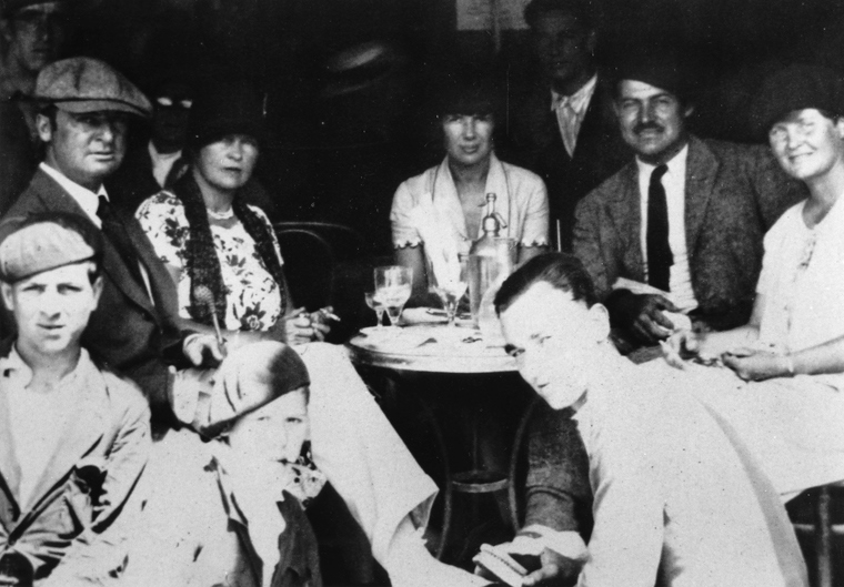 siete personas sentadas tomando café en la terraza dekl café kutz en 1925. Ernest Hemingway es una de ellas